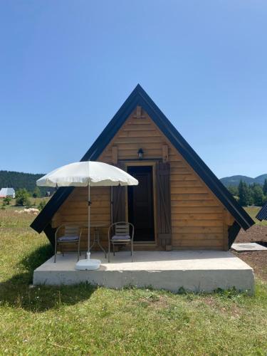 a cabin with two chairs and an umbrella at Podgora 1 in Žabljak