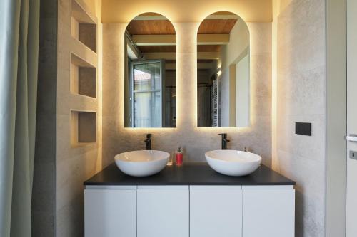 two sinks in a bathroom with two mirrors at PrimoPiano - Zumbini G in Milan