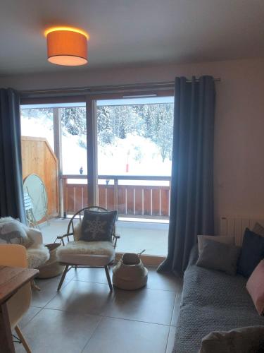 un salon avec un canapé et une grande fenêtre dans l'établissement Appartement neuf, balcon plein sud, à Oz
