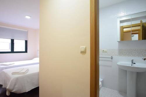 Un baño con una cama, un lavabo y un espejo. en Apartmento O Pindo, en O Pindo