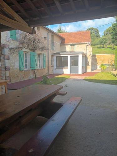 une table de pique-nique en bois devant un bâtiment dans l'établissement Maison de campagne, à Lindry