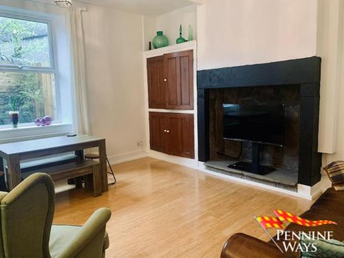 a living room with a television and a fireplace at The Old Courthouse Cottage, Haltwhistle in Haltwhistle