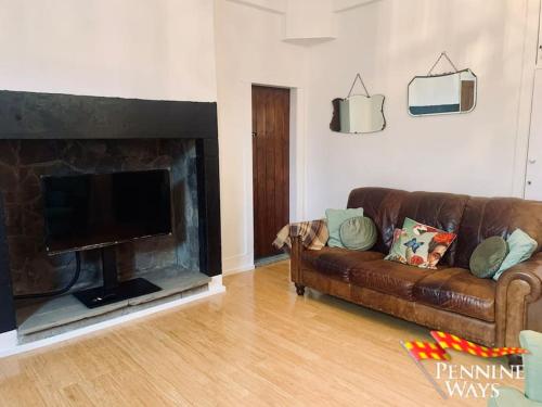 a living room with a brown couch and a fireplace at The Old Courthouse Cottage, Haltwhistle in Haltwhistle