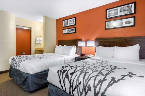two beds in a hotel room with orange walls at Sleep Inn Sarasota North in Sarasota