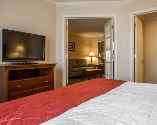 a bedroom with a bed and a flat screen tv at Clarion Inn & Suites at the Outlets of Lake George in Lake George