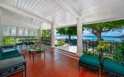 a porch with chairs and tables and a view of the ocean at Clearwater home in Saint Peter