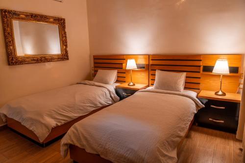 two beds in a room with a mirror and two lamps at Hotel D'Europe Centre Ville in Kenitra