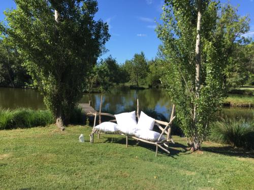 un canapé blanc assis sur l'herbe à côté d'un lac dans l'établissement Marais de capeau, à Arles