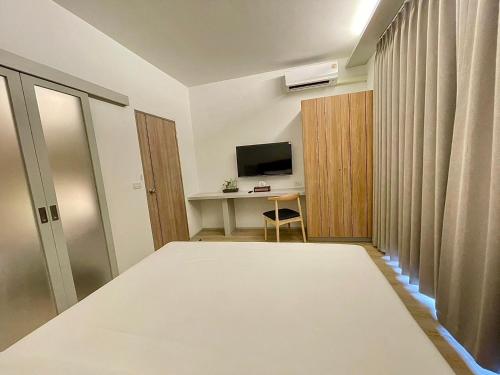 a room with a bed and a desk with a television at At Thaphae Hostel in Chiang Mai