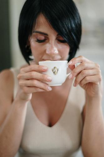a woman is holding a cup of coffee at Palascìa Wellness Relais in Otranto