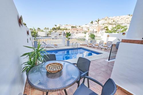 a patio with a table and chairs and a swimming pool at Villa Pura - Private Jacuzzi & Heated Pool in Nerja