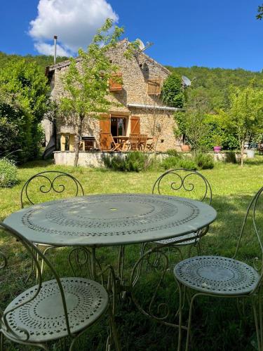 a table and two chairs in front of a house at La métairie basse Dordogne 2 Gites pour 18 personnes au total in Saint-Aubin-de-Nabirat