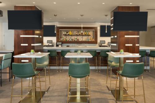 a bar with green chairs and tables in a restaurant at DoubleTree by Hilton Miami North I-95 in Miami