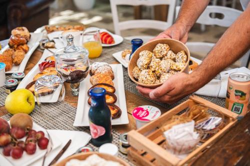 a man holding a bowl of food on a table with food at Palascìa Wellness Relais in Otranto