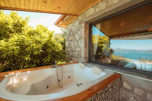 a bath tub in a room with a large window at Faralya Yoruk Evi Suite in Faralya