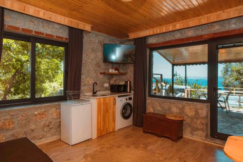 a kitchen with a washing machine in a room with windows at Faralya Yoruk Evi Suite in Faralya