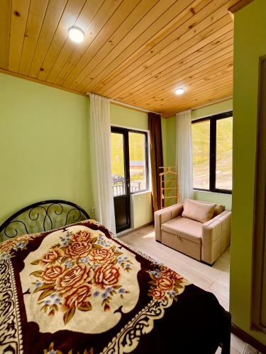 a bedroom with a large bed and a couch at Gamarjoba Guest and Art House in Ushguli