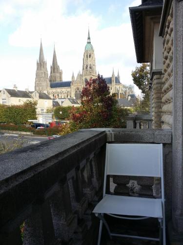 a white chair on a balcony with a view of a city at Le Castel Guesthouse in Bayeux