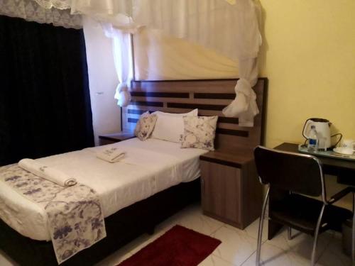 Una habitación de hotel con una cama, una mesa y una silla. en Akuka Lodge, en Zomba