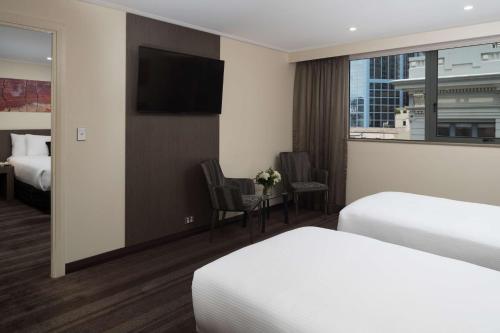 a hotel room with two beds and a flat screen tv at Rydges World Square in Sydney