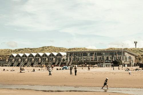 a group of people on a beach with buildings in the background at Strandhuisjes Zoomers aan Zee in Castricum