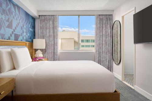 a bedroom with a large white bed and a window at OUTRIGGER Waikiki Paradise Hotel in Honolulu