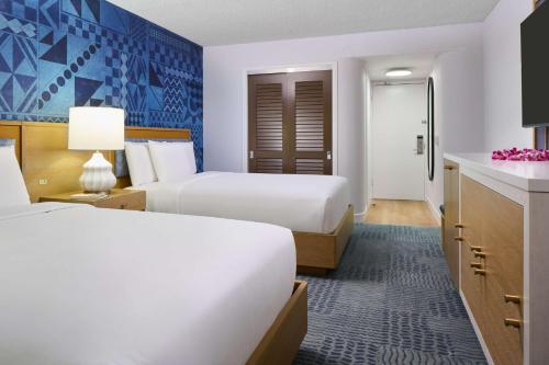 a hotel room with two beds and a kitchen at OUTRIGGER Waikiki Paradise Hotel in Honolulu