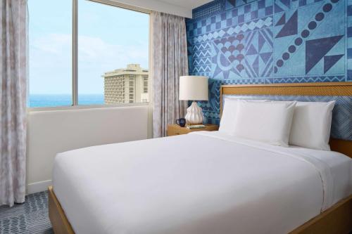 a bedroom with a large bed and a window at OUTRIGGER Waikiki Paradise Hotel in Honolulu