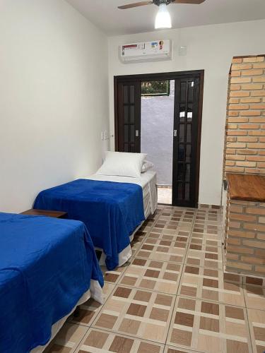 two beds in a room with blue sheets at Pousada Vila Boiçucanga in Boicucanga