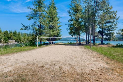 an empty volleyball court with trees and water in the background at RiverPoint Retreat in Sandpoint
