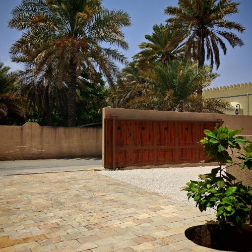 a wooden gate in a yard with palm trees at نزل عِطره Etra Inn in Nizwa