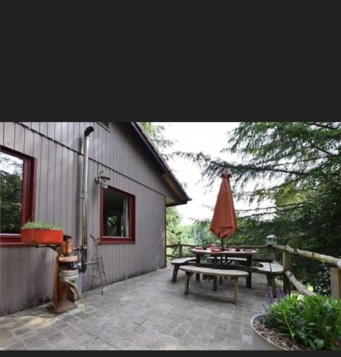 a patio with a picnic table and an umbrella at Agréable chalet en pleine nature in Houffalize