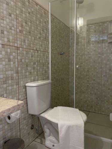 a bathroom with a toilet and a glass shower at Pousada Vila Boiçucanga in Boicucanga