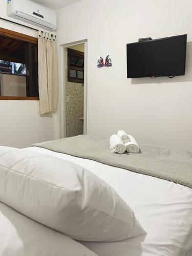 a bedroom with two beds and a flat screen tv at Pousada Vila Boiçucanga in Boicucanga