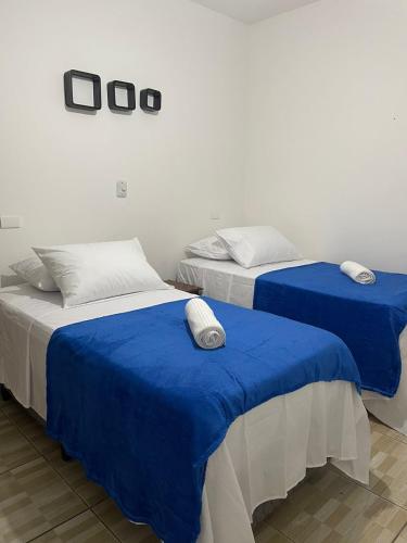 two beds in a room with blue sheets at Pousada Vila Boiçucanga in Boicucanga