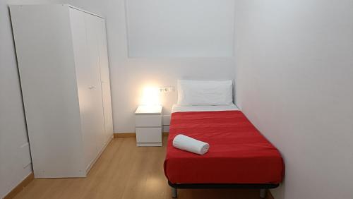 a small room with a bed with a red blanket at Sant Jordi Pisos - Consell de Cent in Barcelona