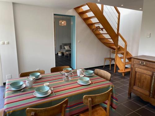 une salle à manger avec une table et des chaises et un escalier dans l'établissement Maison avec vue mer et accès plage à Plougasnou, à Plougasnou