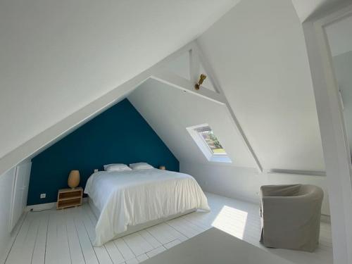 - une chambre avec un lit blanc et un mur bleu dans l'établissement Maison avec vue mer et accès plage à Plougasnou, à Plougasnou