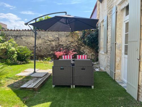 un parapluie posé sur l'herbe à côté d'une maison dans l'établissement Charmante charentaise, à Saint-Jean-dʼAngély