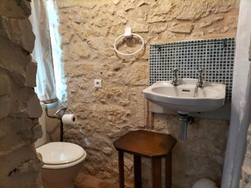 une salle de bain en pierre avec un lavabo et des toilettes dans l'établissement Chambre d'hôtes en Dordogne proche Eymet, à Fonroque