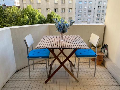 une table avec deux chaises et un vase de fleurs sur le balcon dans l'établissement Appartement spacieux Paris Vanves Parc des expositions, à Vanves