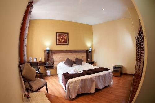 a hotel room with a bed and a chair at Hotel Arequipa Vive in Arequipa