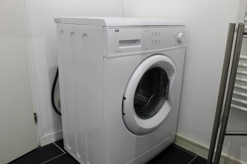 a white washing machine in a laundry room at La Briquette - WIFI - PARKING - Proche de Lille in Carvin