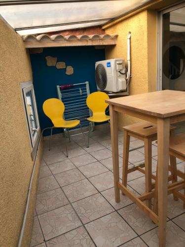 un patio avec des chaises jaunes, une table et un radiateur dans l'établissement Mistral 2 étage D avec clim, à Coursan