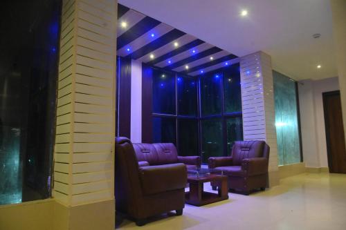 a room with two chairs and a window with purple lights at Hotel Air Inn in Guwahati