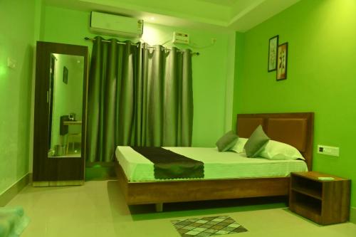 a green bedroom with a bed and a mirror at Hotel Air Inn in Guwahati
