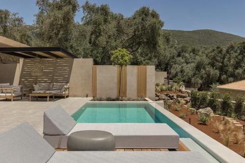 a swimming pool in a yard with chairs and a patio at Monalia suites in Parga
