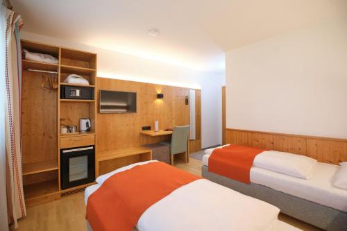 a hotel room with two beds and a desk at Santner, Hotel in Eugendorf