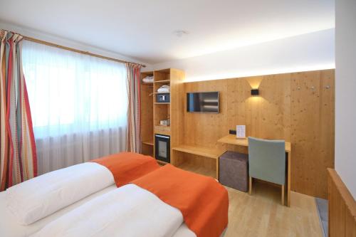 a bedroom with a bed and a desk and a television at Santner, Hotel in Eugendorf