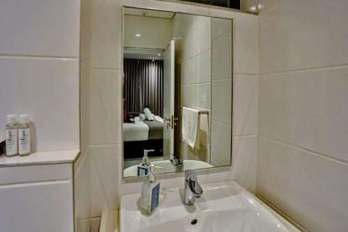 une salle de bain blanche avec un lavabo et un miroir dans l'établissement Tranquility meets serenity, à Ballito